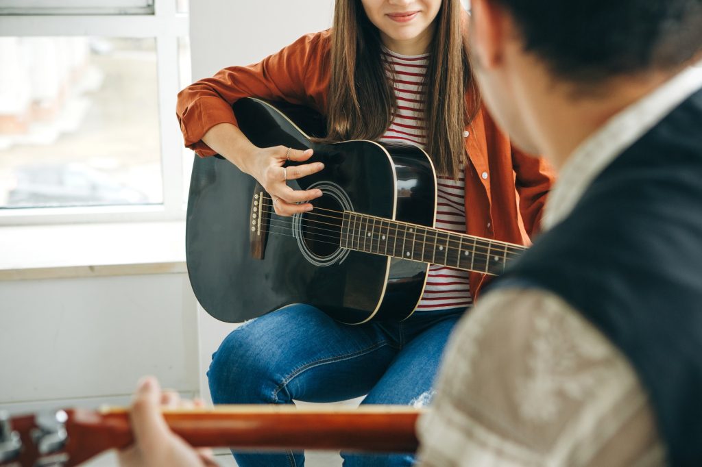 Learning to play the guitar. The teacher explains to the student the basics of playing the guitar. Individual home schooling or extracurricular lessons.